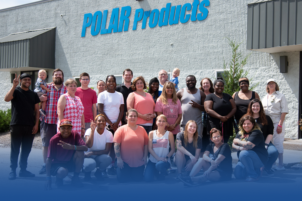 Group of people posing in front of a building with 'Polar Products' signage.