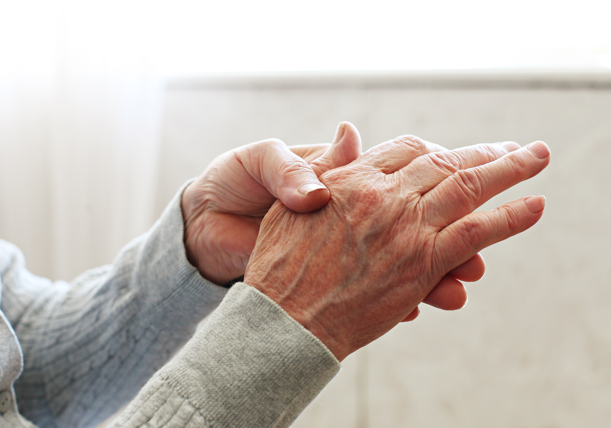 Close-up of an elderly person's hands with visible wrinkles and age spots.