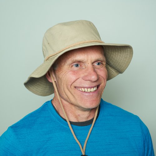 Man wearing a beige cooling bucket hat and blue shirt against a light green background