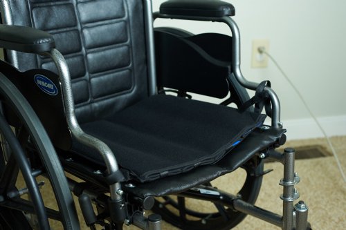 Black wheelchair with a black cooling seat cushion on a carpeted floor.