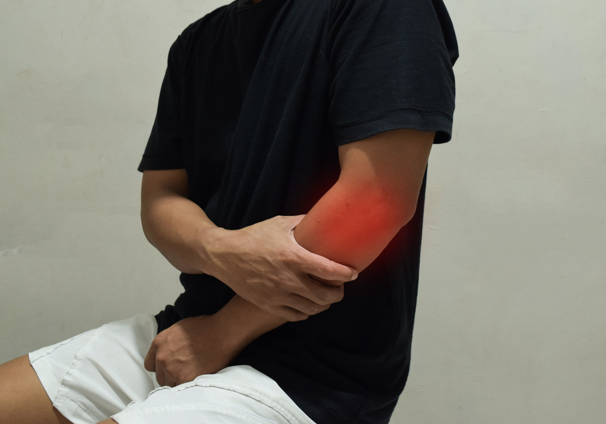 Person holding their elbow with a red mark indicating pain or injury on a plain background