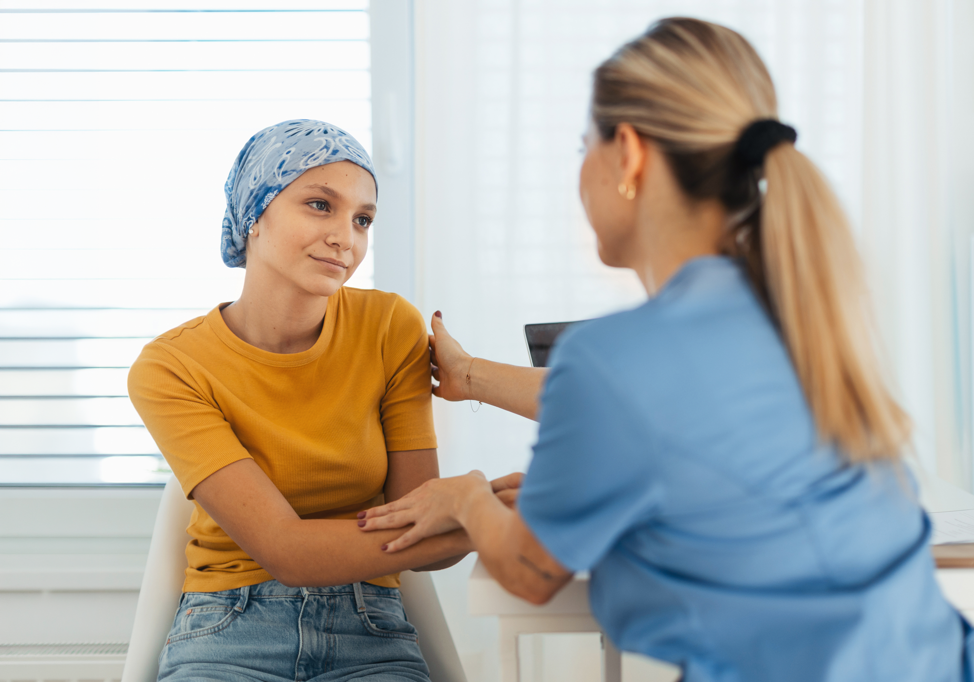 Woman with cancer receiving support from a healthcare professional in a bright room.