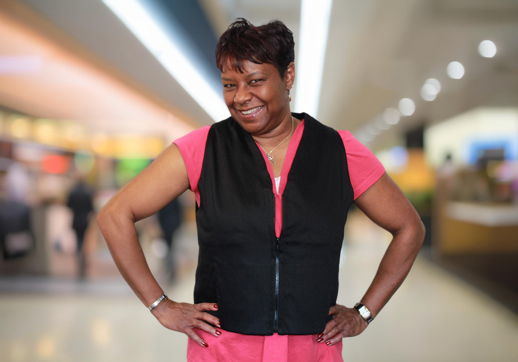 Woman in a black and pink outfit standing in a blurred indoor setting