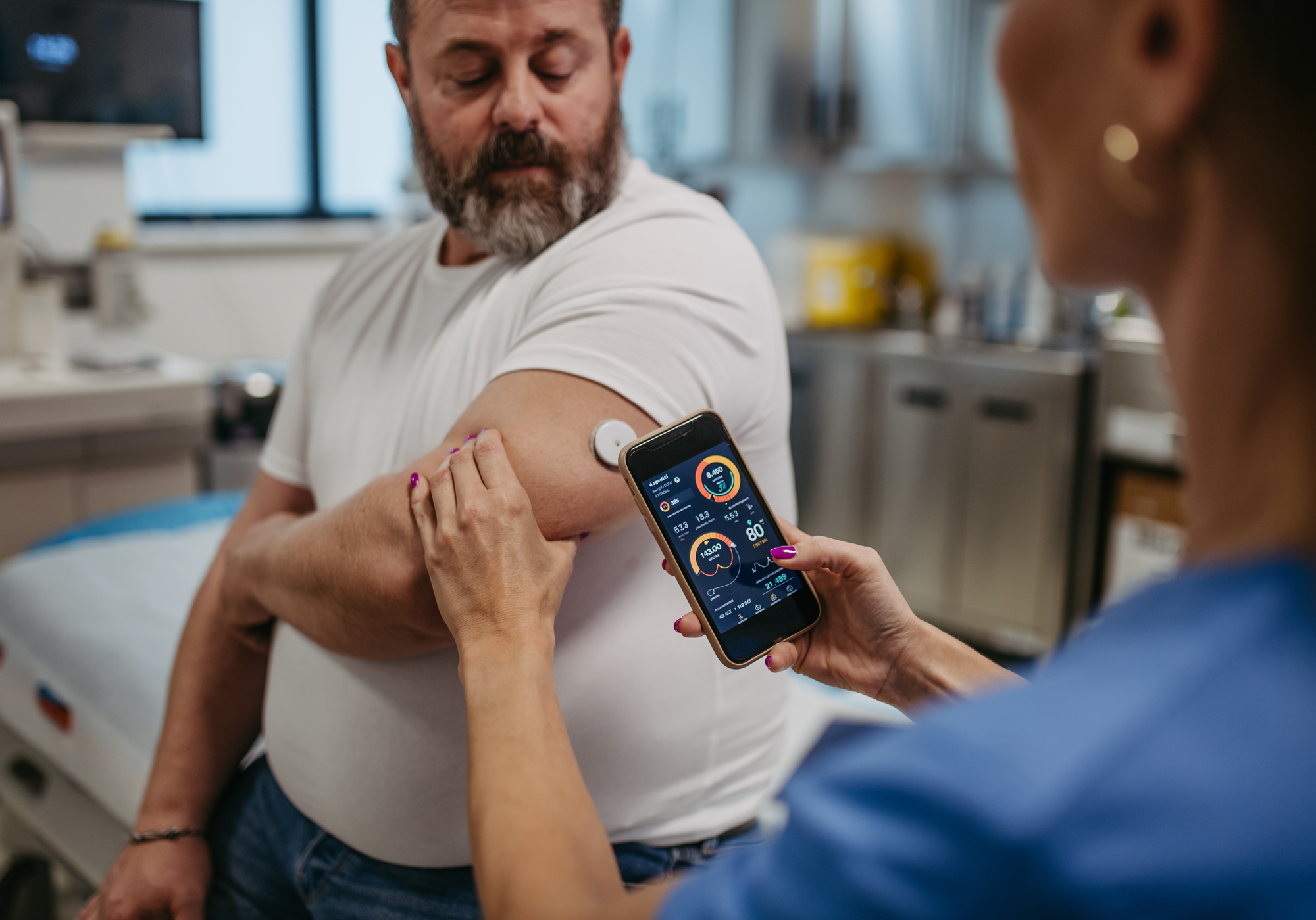 Person using a smartphone app for diabetes on a man's arm in a medical setting