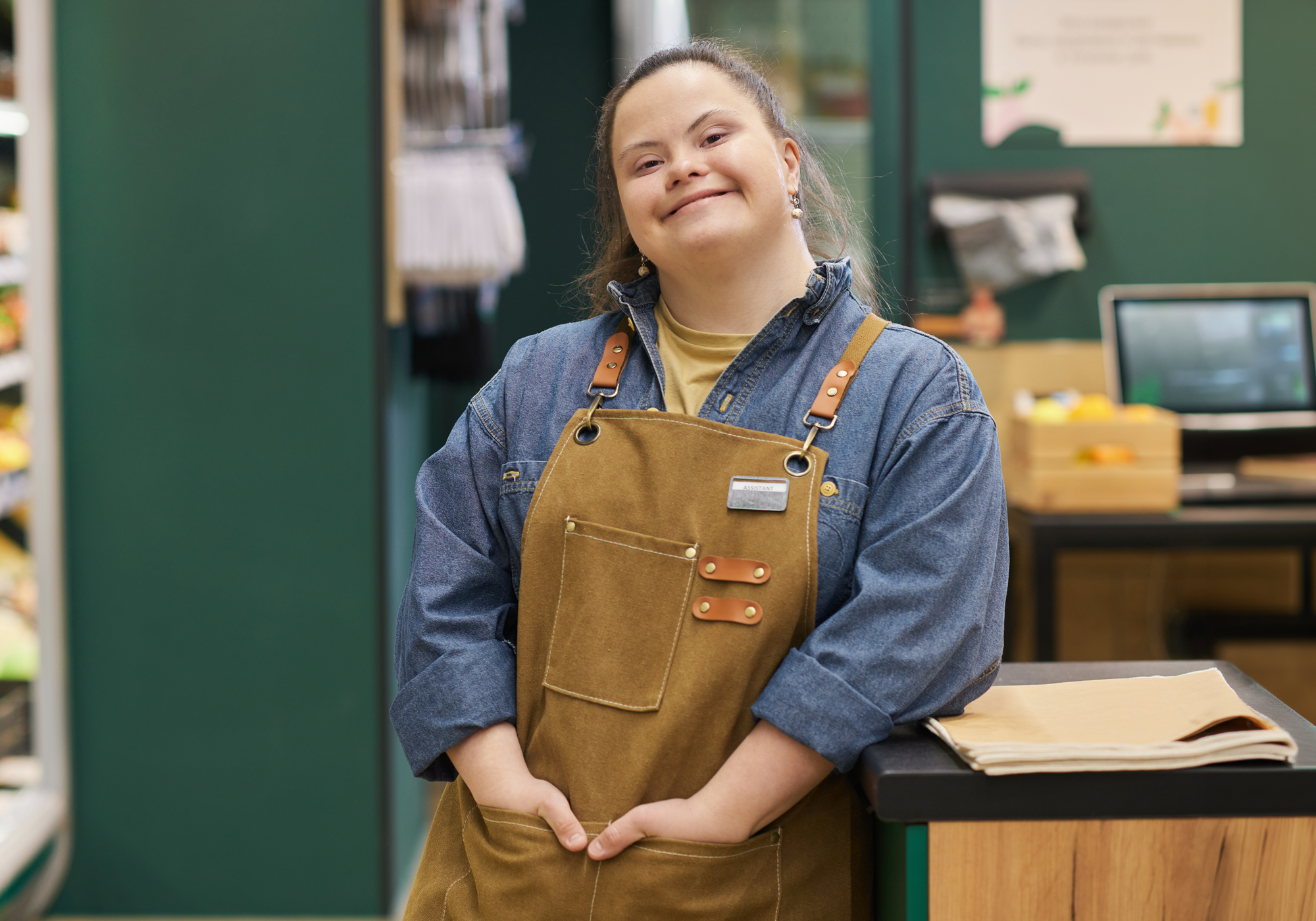 Person wearing a brown apron and blue shirt in a store setting
