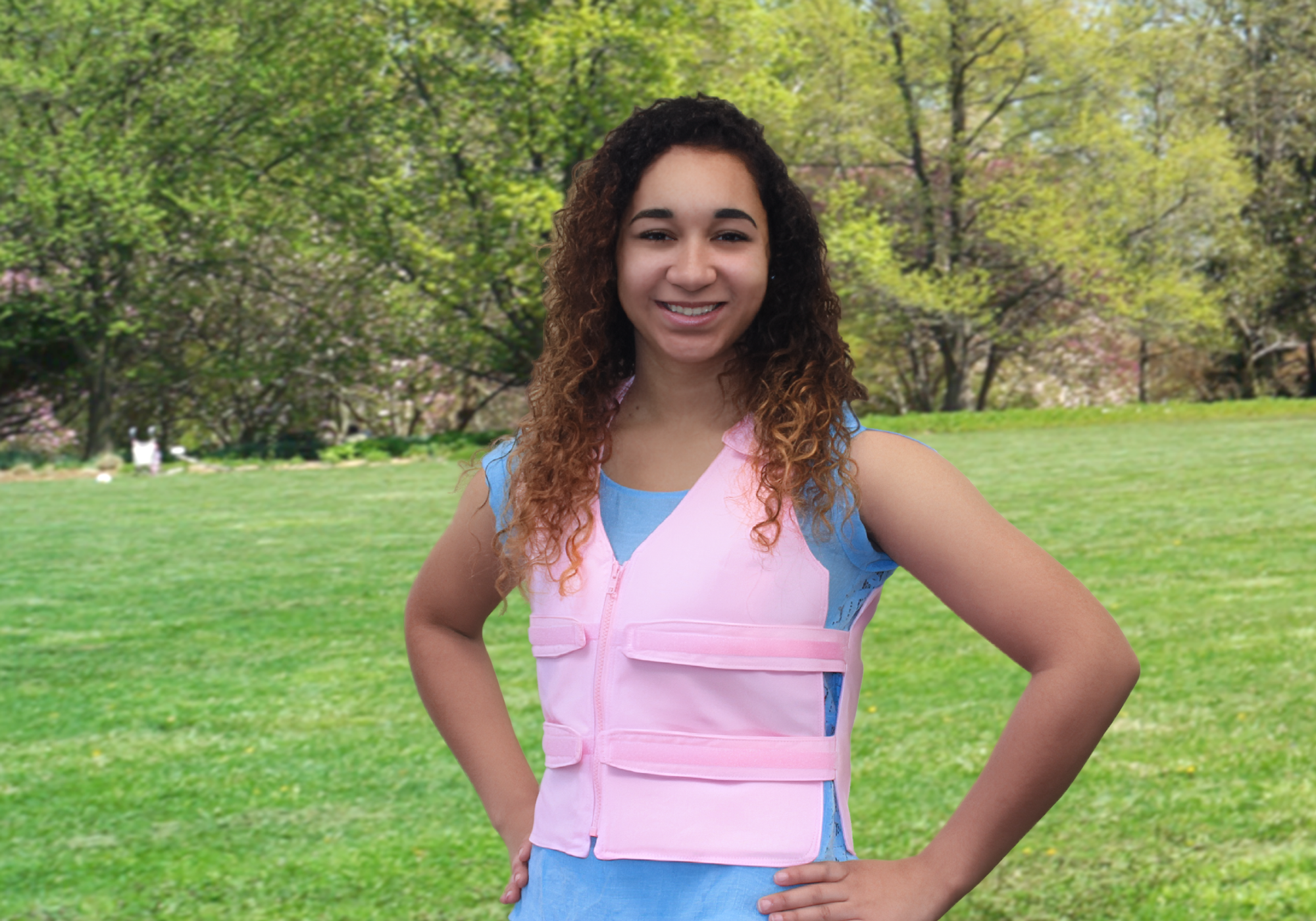 Teenage girl wearing a pink adjustable cooling vest outside in a park.