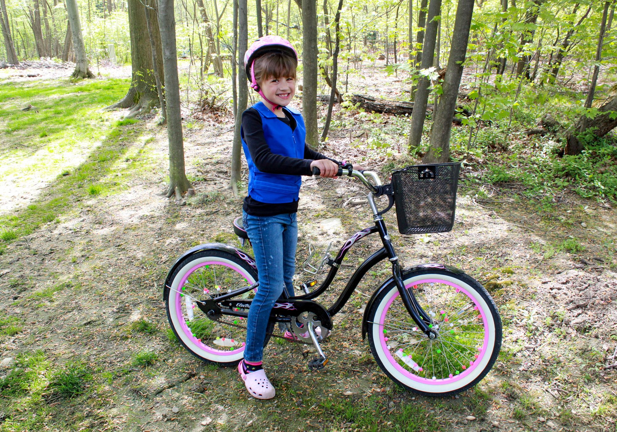 a young girl sits on her bike wearing a cooling vest.