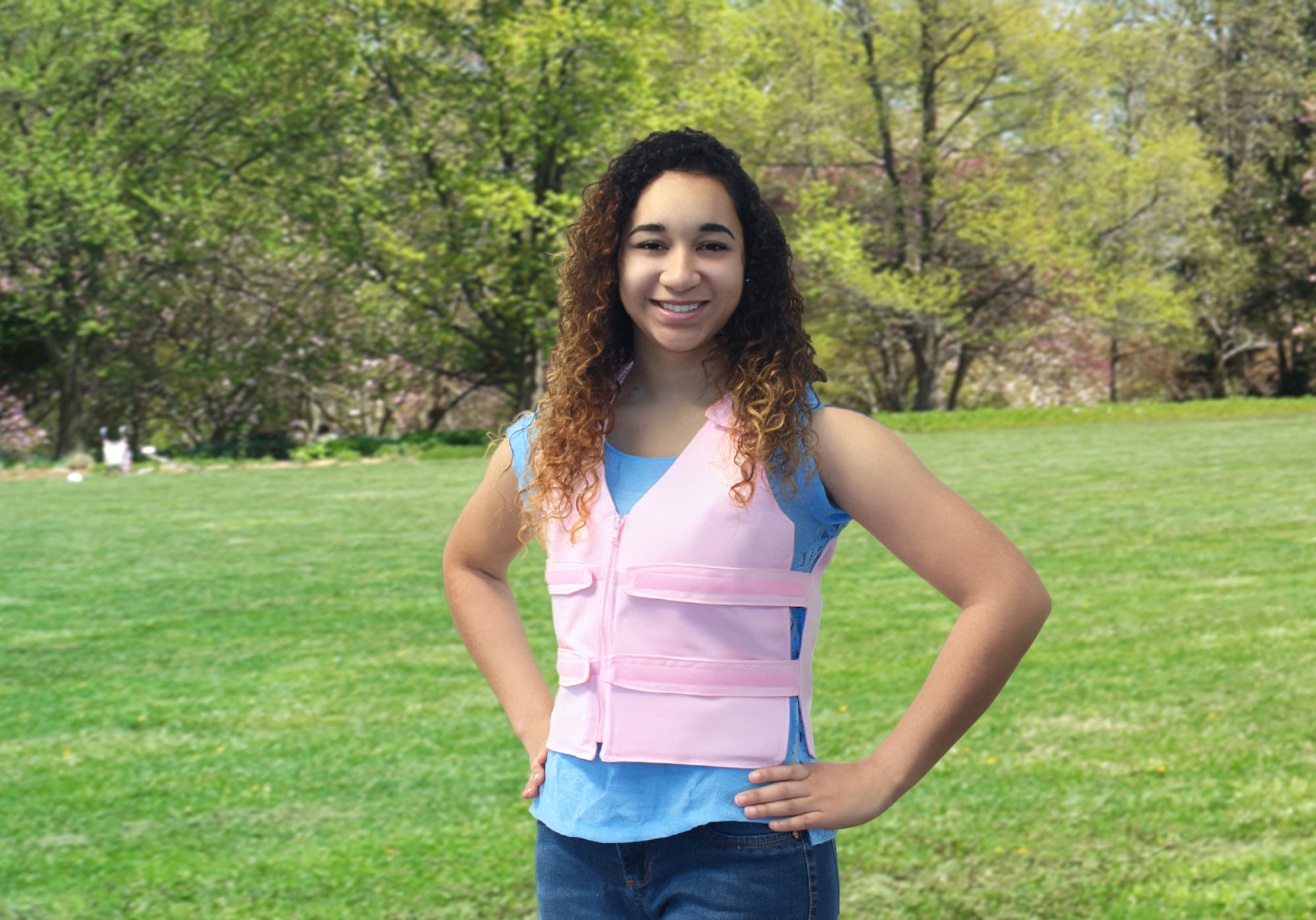 Person wearing a pink cooling vest over a blue shirt in a grassy outdoor setting