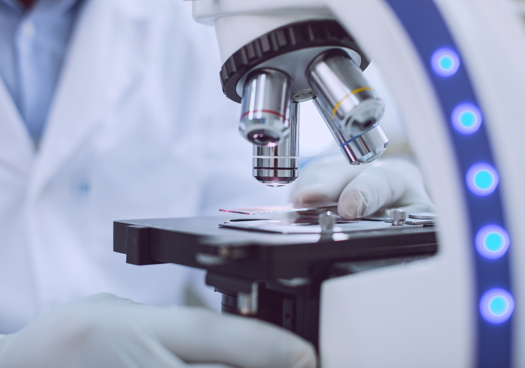 Microscope with a person wearing gloves in a laboratory setting