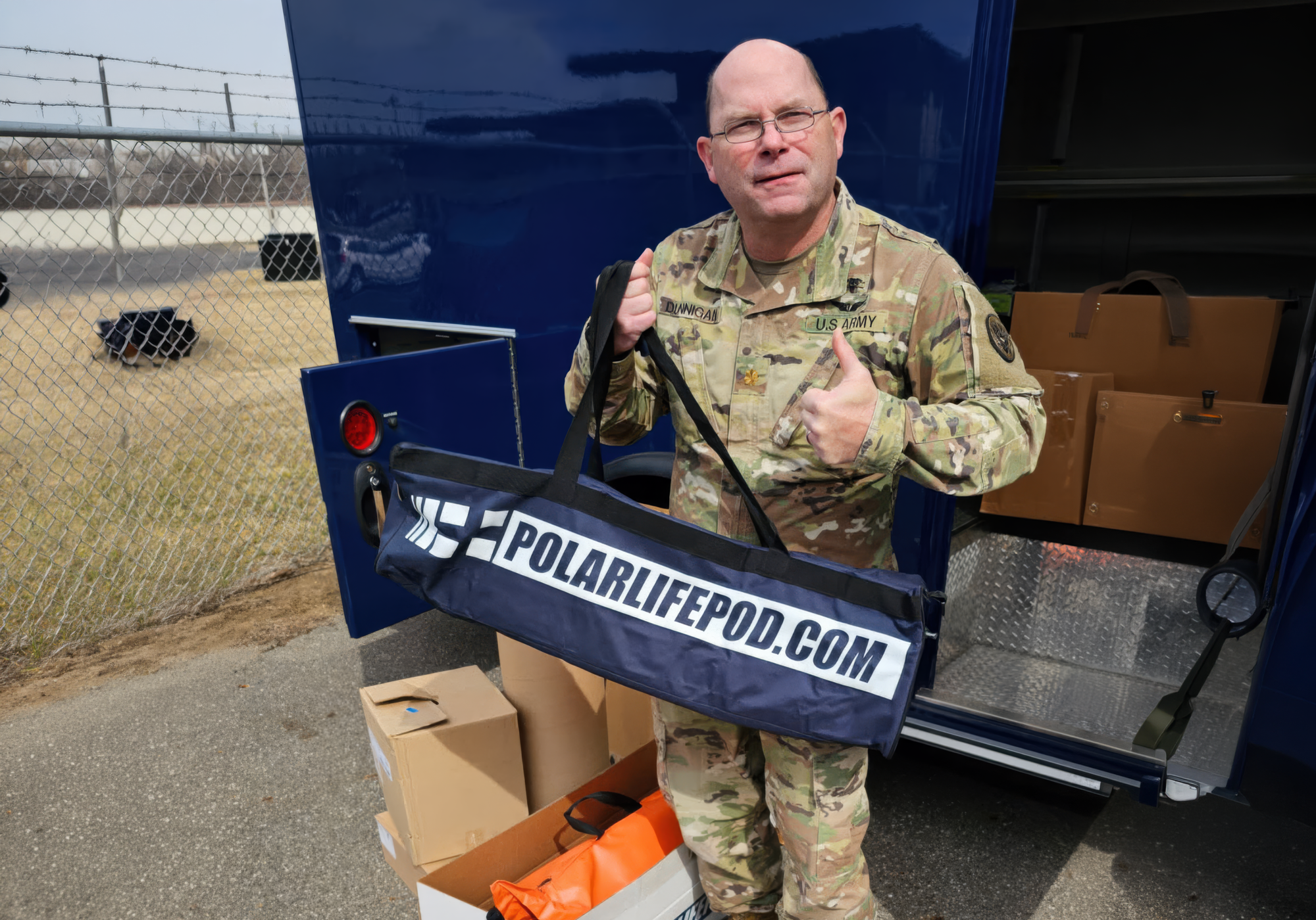 Person in military uniform holding a 'PolarLifePod' product with a trailer in the background