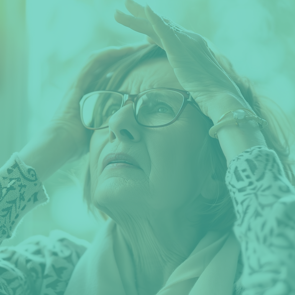 Woman with glasses holding her head, teal filter applied