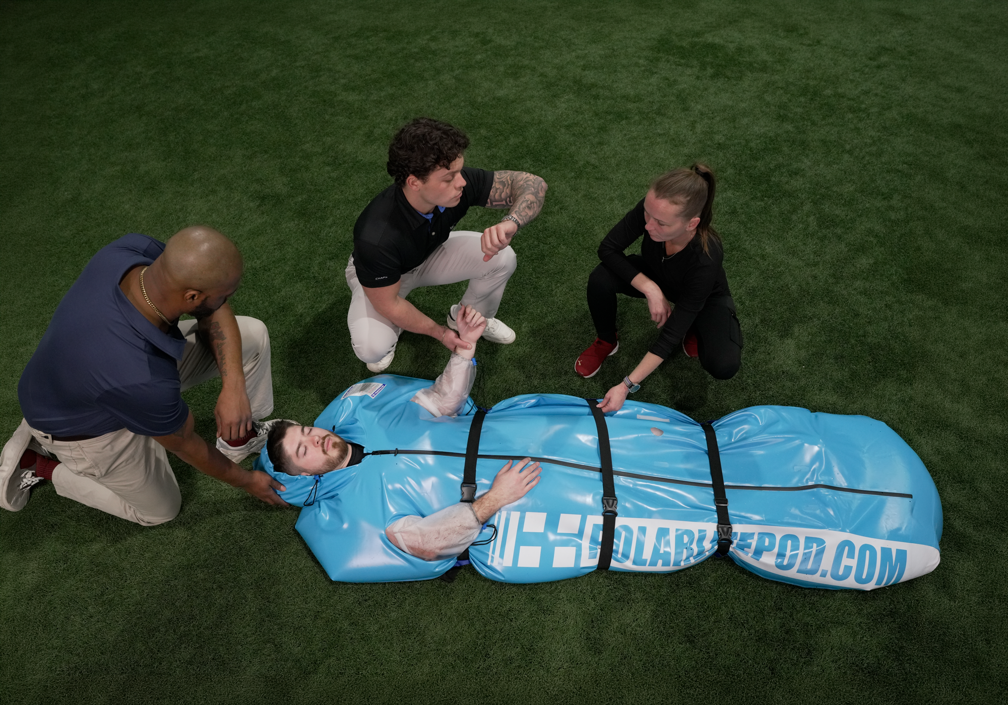 Person being rescued by a team using a blue rescue pod on a grassy field