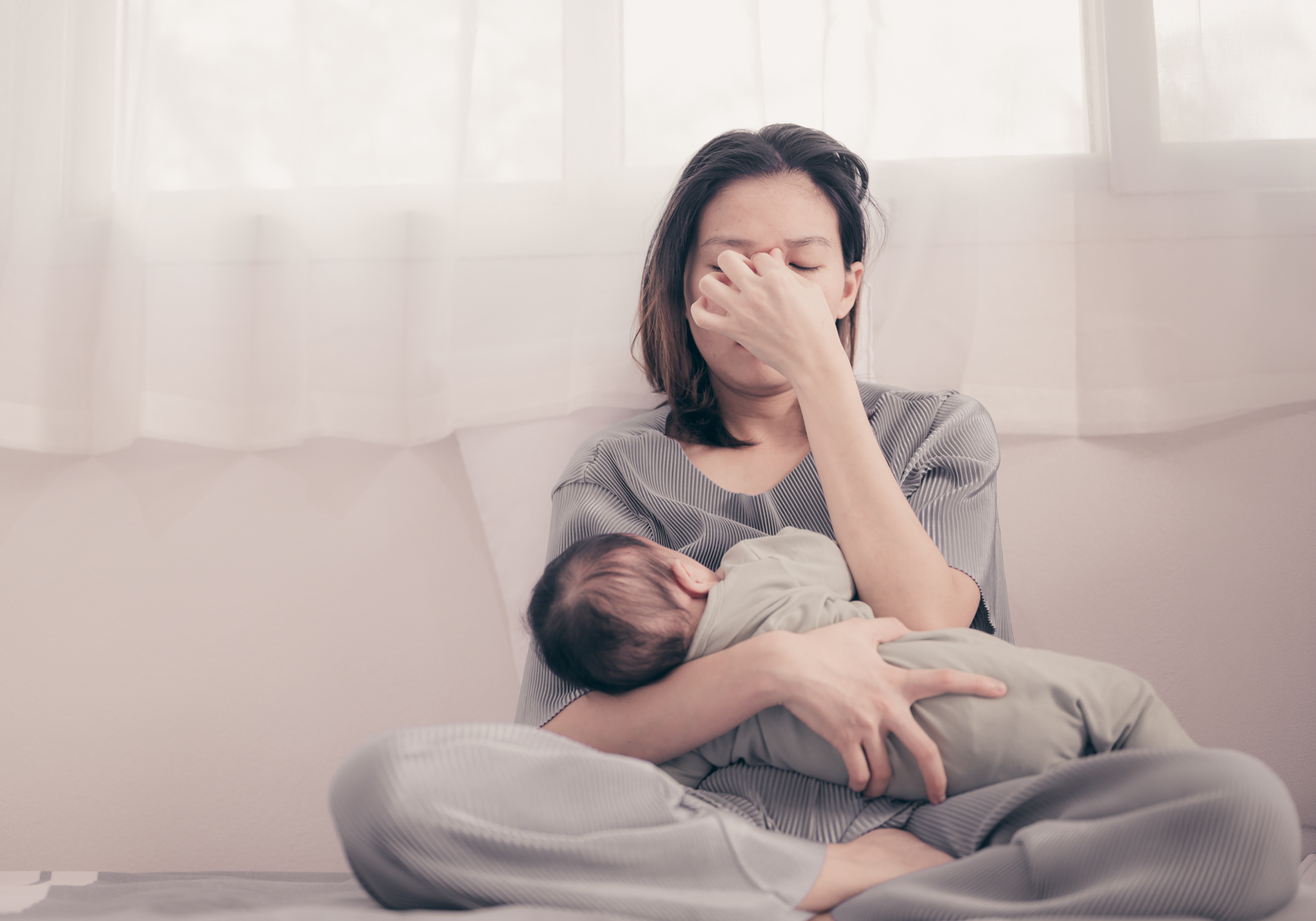 Woman breastfeeding a baby on a couch in a bright room