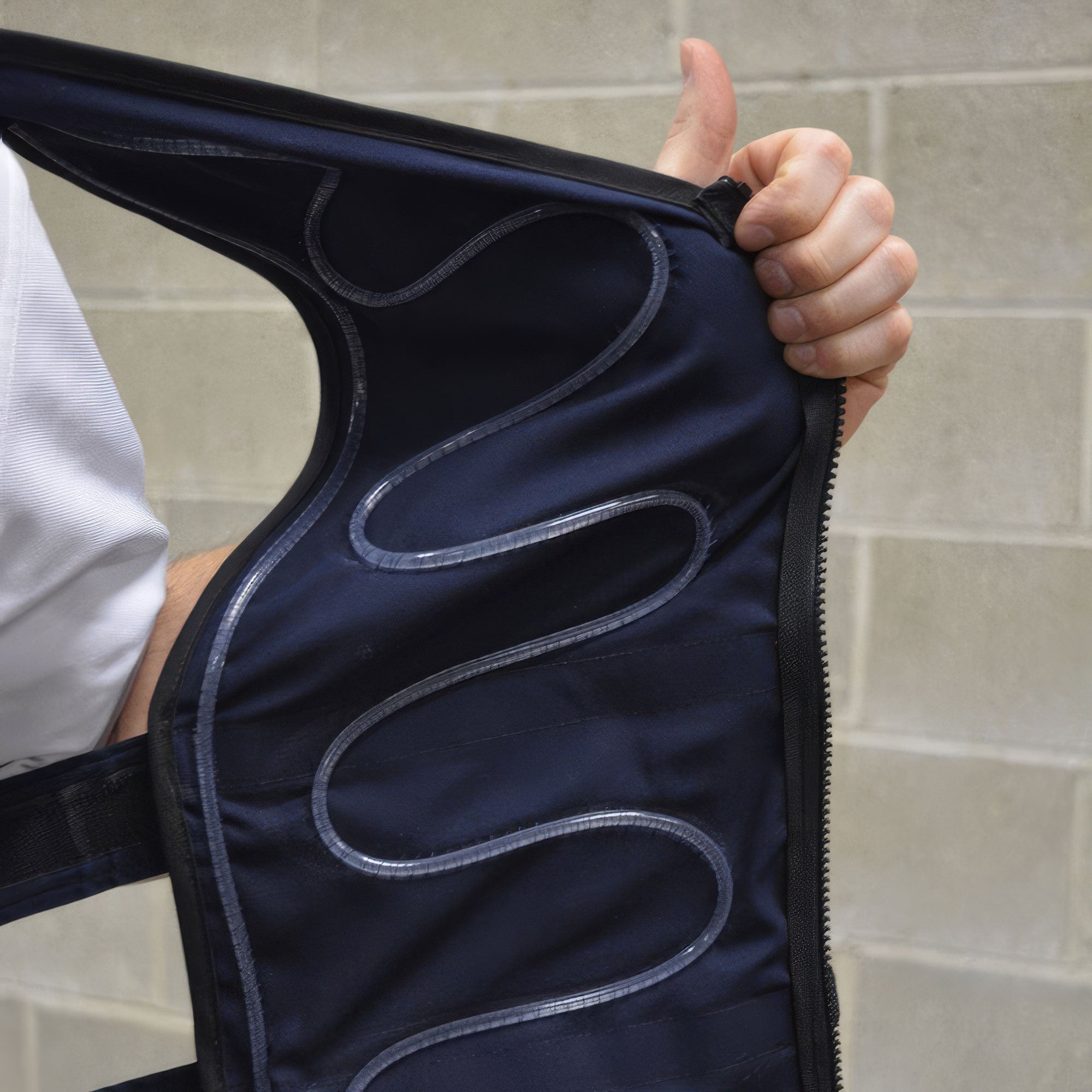 Person holding a navy blue garment with wavy white lines against a tiled wall.