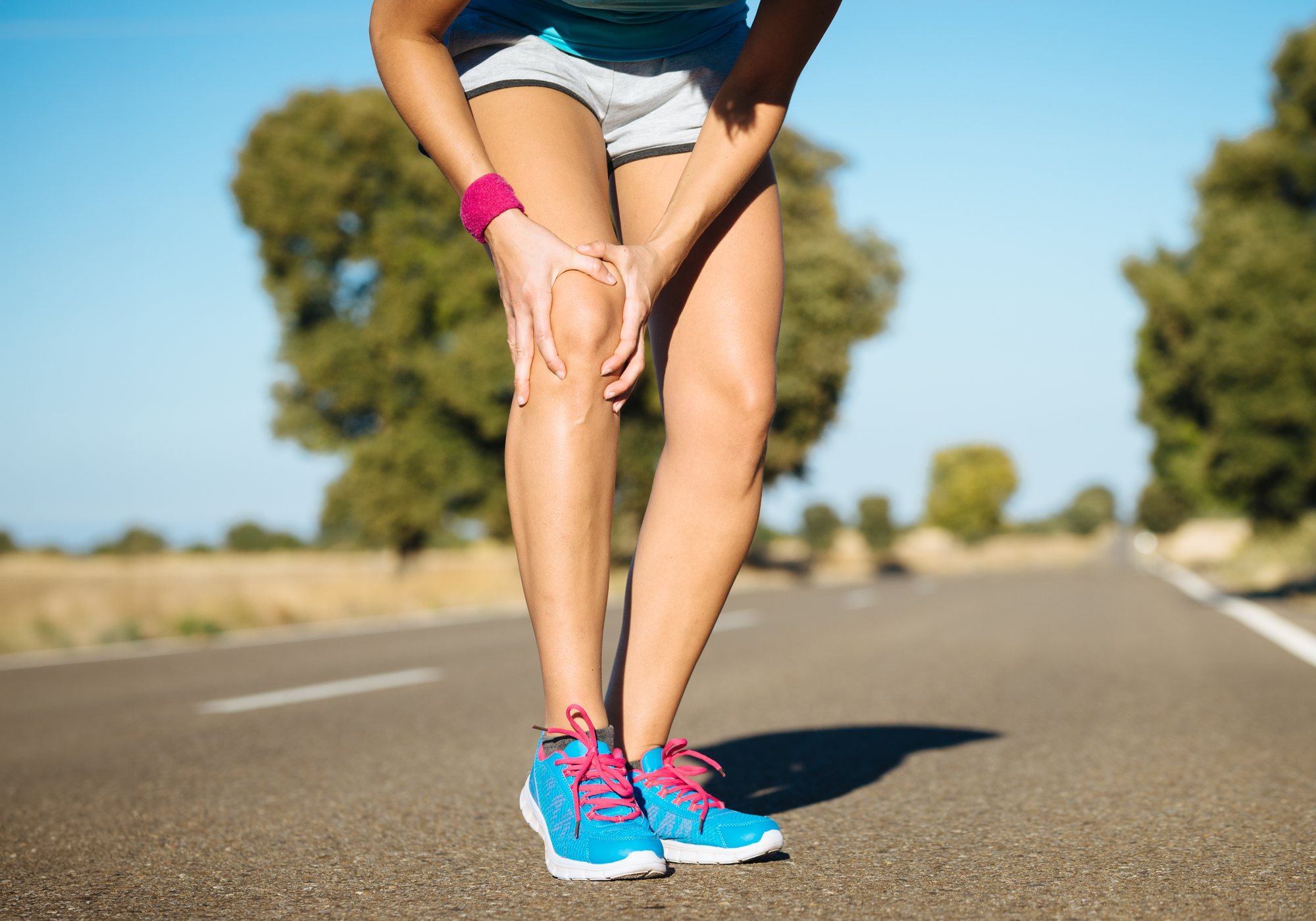 Person with a knee injury on a road with trees in the background