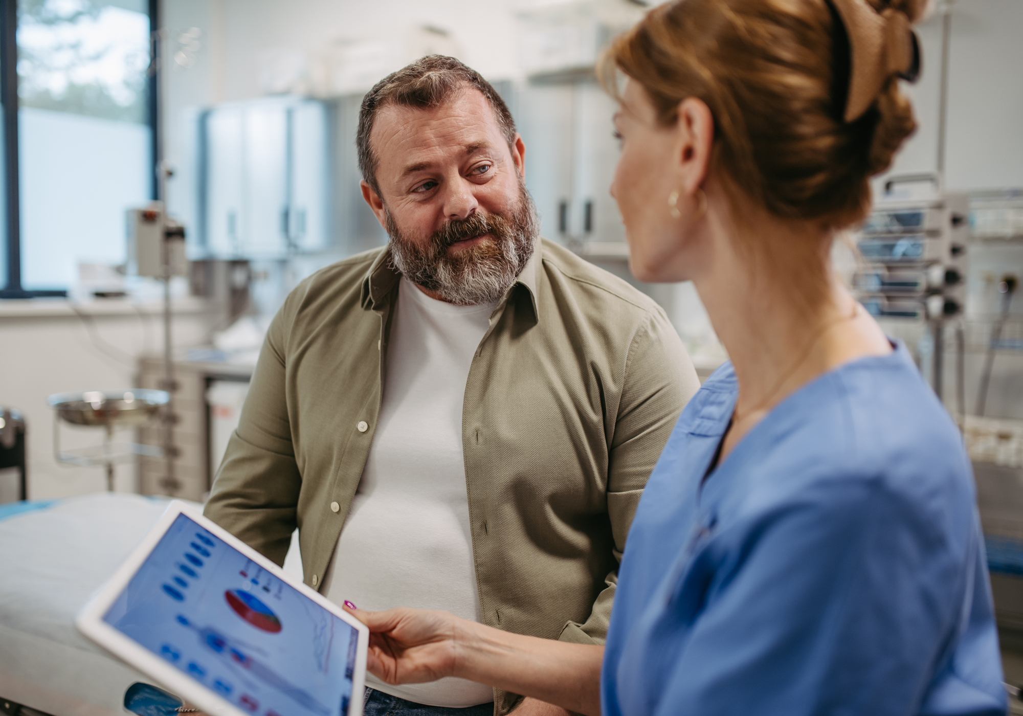 Man with a tablet interacting with a healthcare professional in a clinical setting